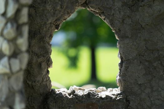 stone background with window and view of blurred green tree.