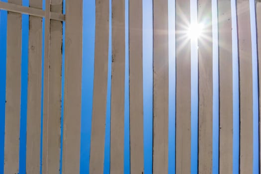 Natural background of white boards against the blue sky, the sun shines through the cracks.