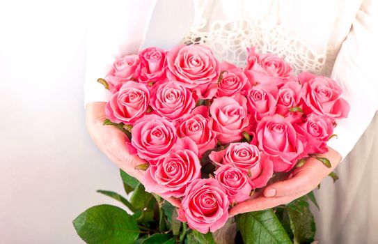 bouquet of pink roses in the shape of a heart in female hands