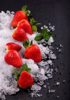 Strawberries, mint and iceon the black background.