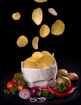 Potato chips on a dark wooden board. Fast food. Dark background. Top view