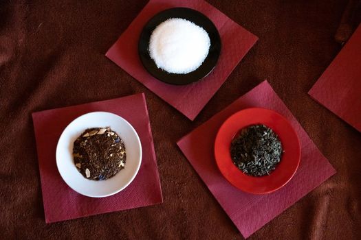 Three dishes with sugar, tea, and shading on red napkins and brown tablecloth