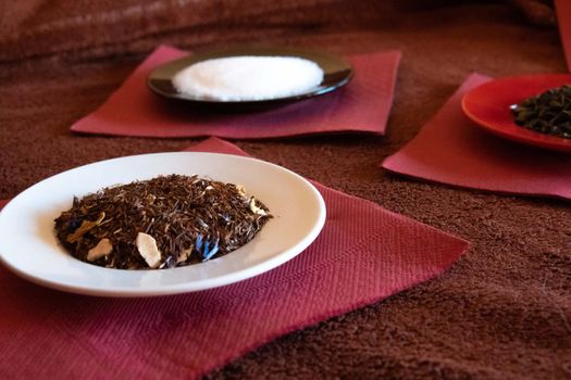 Three dishes with sugar, tea, and shading on red napkins and brown tablecloth