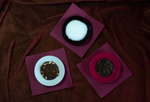 Three dishes with sugar, tea, and shading on red napkins and brown tablecloth