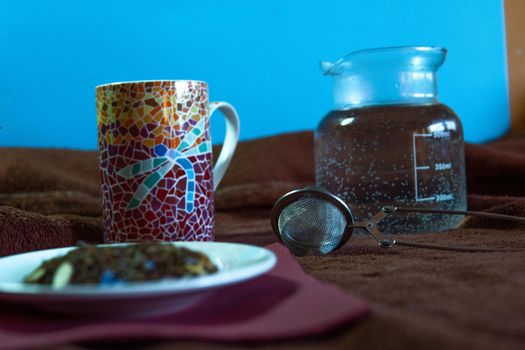 Tea cup with plate and spices with a transparent jug with water