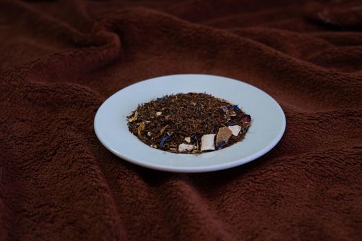 White plate with natural tea on a brown background