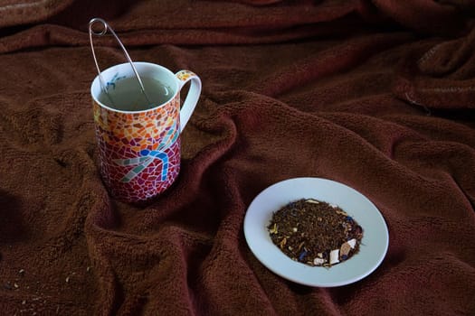 Making a tea in a colorful cup and a white saucer with natural tea