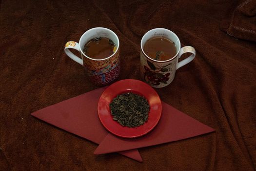 Saucer with natural black tea and two cups with freshly made tea