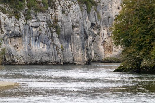 Danube valley at Danube breakthrough near Kelheim, Bavaria, Germany in autumn with plants with red leaves in foreground and limestone formations in the background