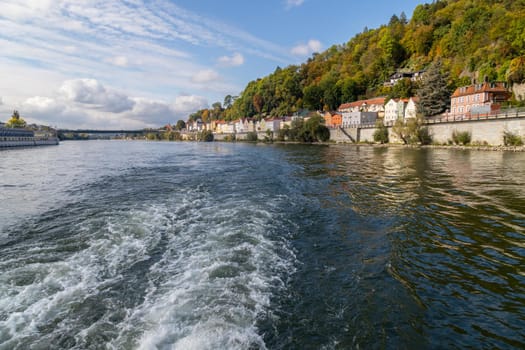 View at Danube shore in Passau during a ship excursion in autumn with multicolored trees 