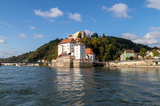 View at Danube shore with entry of river Ilz into Danube in Passau during a ship excursion in autumn with multicolored trees 