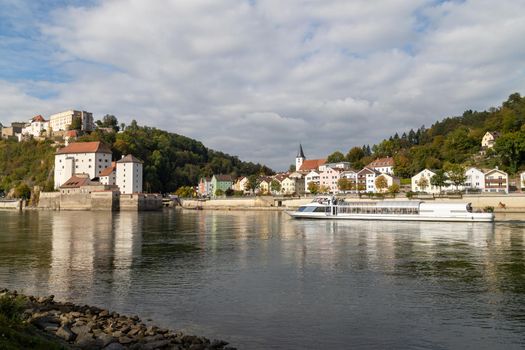 View at Fortress Veste Oberhaus, Danube shore and entry of river Ilz in Passau, Bavaria, Germany in autumn with Danube river and passenger ship