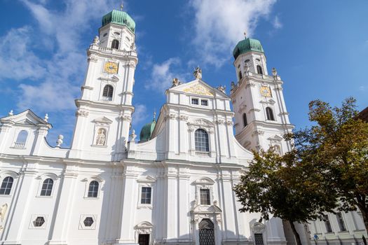 The front of St. Stephen's Cathedral (Dom St. Stephan) in Passau, Bavaria, Germany in autumn with multicolored tree in foregound