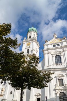 The front of St. Stephen's Cathedral (Dom St. Stephan) in Passau, Bavaria, Germany in autumn with multicolored tree in foregound