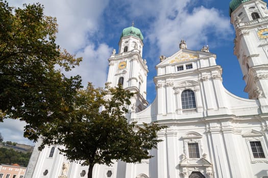 The front of St. Stephen's Cathedral (Dom St. Stephan) in Passau, Bavaria, Germany in autumn with multicolored tree in foregound