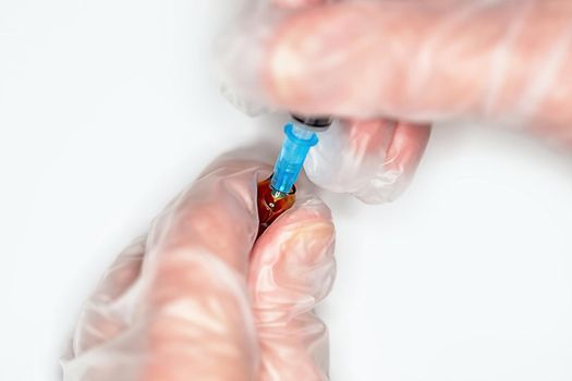 Close-up of a nurse picking up a syringe with medicine for an injection.