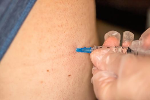 Close-up of a nurse's hands and a syringe that makes an injection into the buttock of a medicinal product