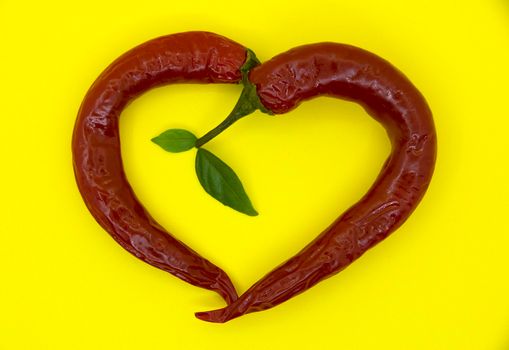 Hot heart of hot red pepper on a yellow background.