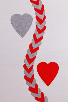 Saint Valentine's day love themed flat-lay design with red and silver heart shapes on textured white background
