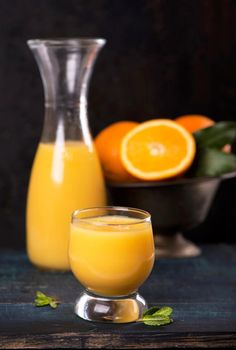 glass of fresh orange juice with fresh fruits on wooden table