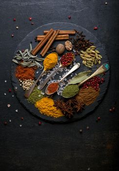 Powder spices on spoons in black wooden table background.