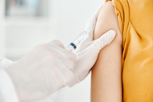a doctor injects a covid-19 vaccine into a woman's shoulder. High quality photo