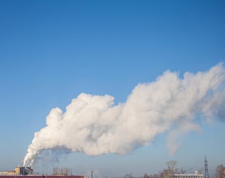 White thick smoke from the boiler room chimney. Smoke against the blue sky. Air pollution. Heating of the city. Industrial zone.