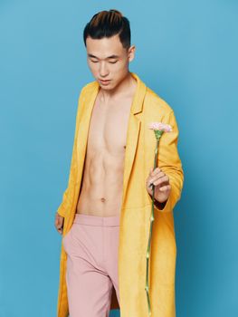 Romantic Asian man with flower and yellow coat and pink pants. High quality photo