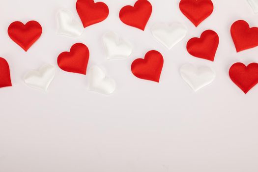 Valentine's day many red and white silk hearts on white background , border frame with copy space, love concept