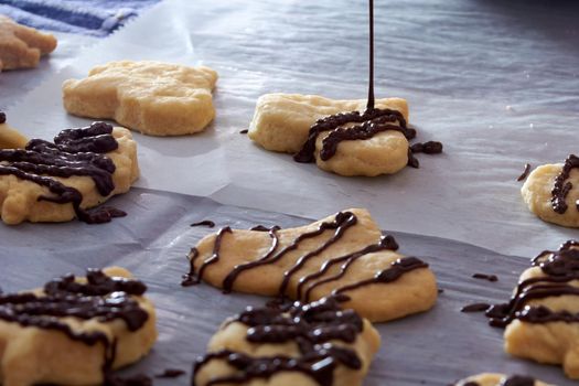 Pouring chocolate on just baked christmas cookies