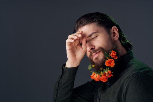 handsome man flowers in a beard decoration romance dark background. High quality photo