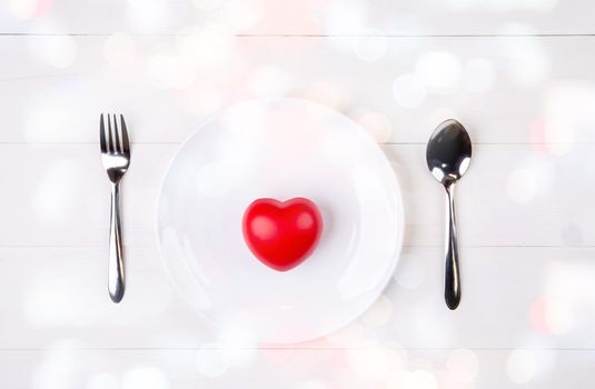 Valentine day, heart shape on dish and utensil with bow for dinner on wooden table, spoon and fork and plate on desk, anniversary and celebration of love, copy space, top view, holiday concept.