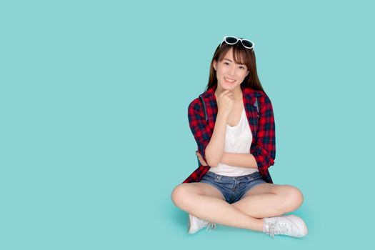 Beautiful portrait young asian woman sitting wear sunglasses on head smile confident thinking and idea summer holiday isolated blue background, asia girl in vacation trip, travel concept.