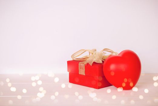 Red gift box and heart shape on wooden table with bokeh background, love and romance, presents in celebration and anniversary with surprise on desk, happy birthday, valentine day concept.