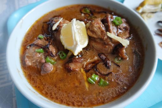 Closeup view of traditional Pakistani Haleem dish with salad and Lemon juice.