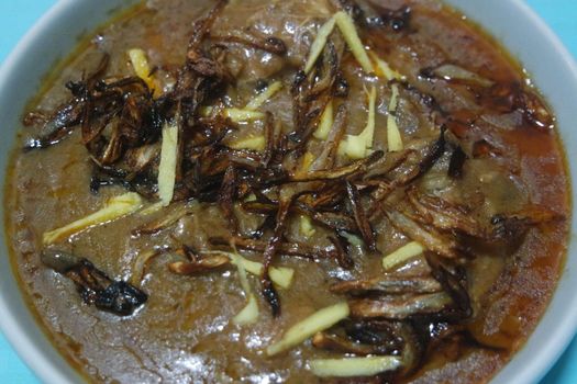 Closeup view of traditional Pakistani Haleem dish with salad and Lemon juice.