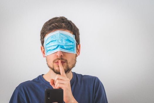 Young angry man with face mask over the eyes is doing a psst! gesture