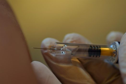 close-up of a hand holding an injection before injecting into the arm