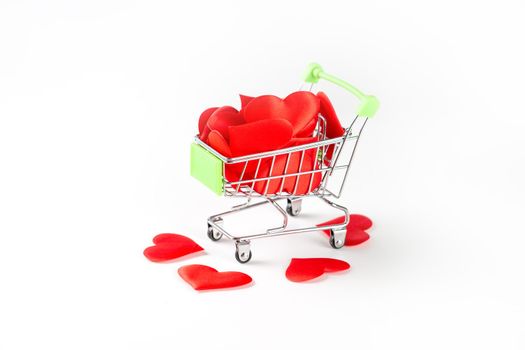 A toy cart from the supermarket filled with red hearts isolated on white background, the concept of love and Valentine's Day.