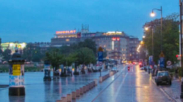 Blurred background. Evening city landscape, city street with lights and passers-by. Creative story for a background, poster, banner, or screensaver.