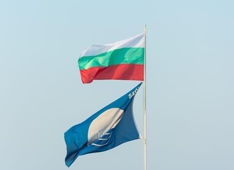 flag of Bulgaria and a clean beach fly on a flagpole against the blue sky
