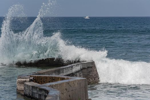 sea wave splashes against a coastal pier. Stock photo
