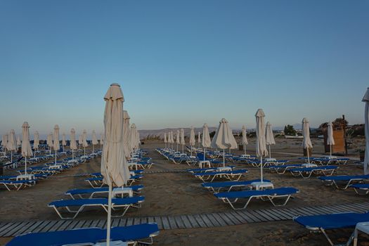 deserted beach with empty sun beds and folded umbrellas. Stock photo