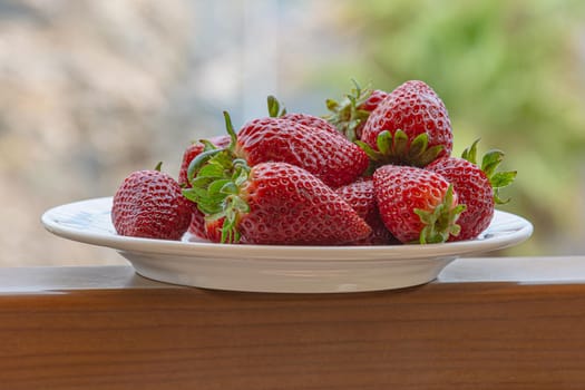 Red ripe strawberries on a plate. Blurry background, close-up. Stock photo