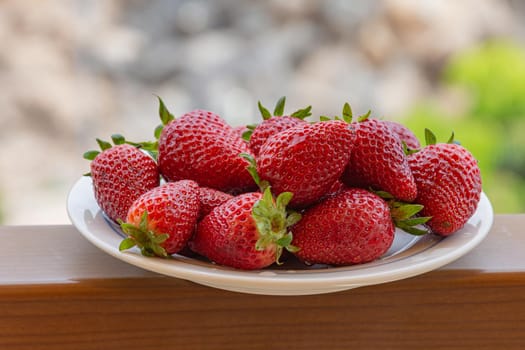 Red ripe strawberries on a plate. Blurry background, close-up. Stock photo
