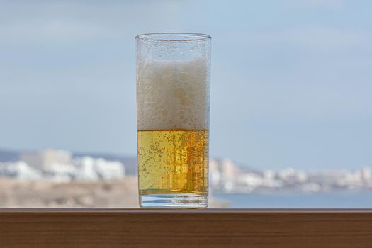 glass of light foamy beer in close-up on a blurry background. Stock photo
