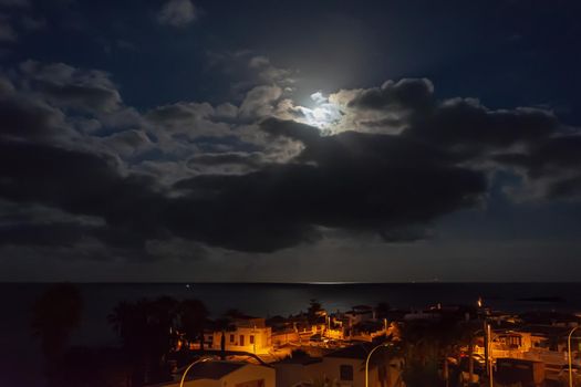 Night landscape. The light of the moon over the sea and the city nightlife. Stock photography