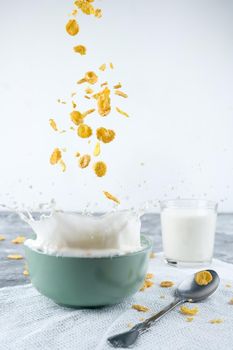 Healthy Breakfast-Cornflakes and Milk Splash on blue background.