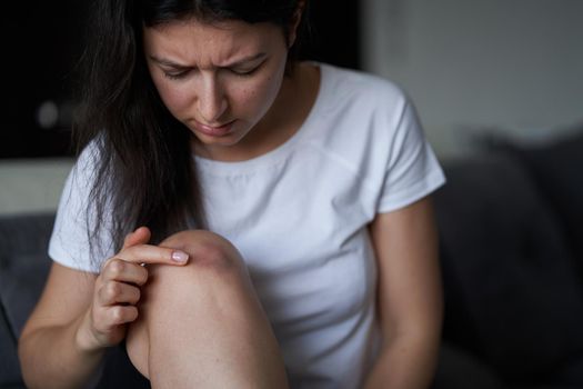 Close-up of a person massaging an injured knee joint. Bruise on the knee. Leg pain.