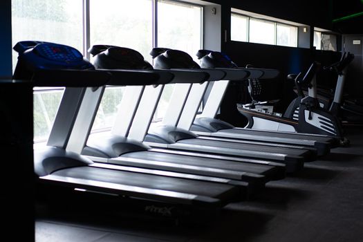 Empty treadmill standing gym near big window Nobody Fitness sport healthy lifestyle concept